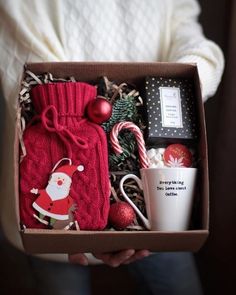 a person holding a christmas gift box with coffee, candy canes and other items