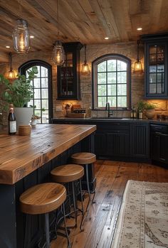 a large kitchen with wooden floors and black cabinetry, along with stools that match the hardwood flooring