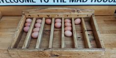 a wooden crate filled with brown eggs sitting on top of a wooden floor next to a sign