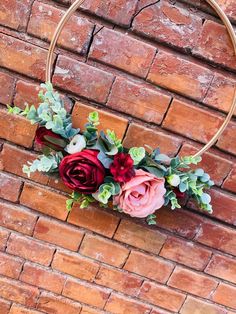 a flower arrangement is hanging on a brick wall in the shape of a hoop with greenery and flowers