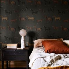 a bedroom with a bed, nightstand and wallpaper that has horses on the wall