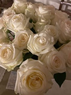 a bouquet of white roses sitting on top of a table