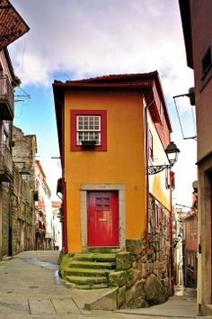 a red door is on the side of a yellow building with steps leading up to it