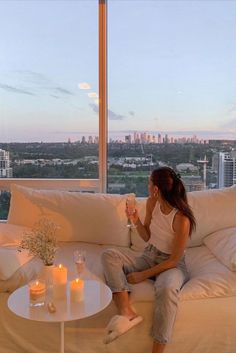 a woman sitting on top of a couch next to a table with candles in it