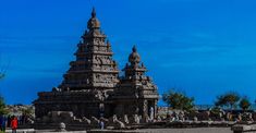 an intricately carved stone structure in the middle of a field with people standing around it