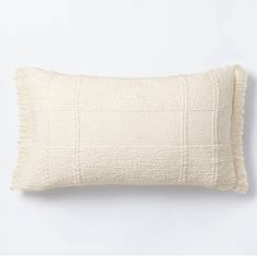 a white pillow with fringes on the front and back, against a white background