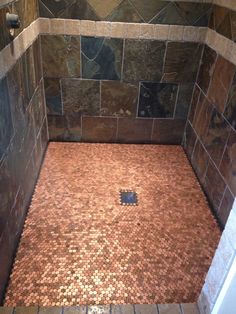 a tiled shower stall with brown and tan tiles on the walls, and a blue square hole in the floor