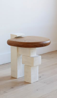 a wooden table sitting on top of a hard wood floor next to a white wall