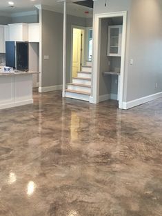 an empty kitchen and living room in a house with white cabinets, marble flooring and stainless steel appliances