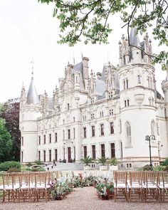 an outdoor wedding setup in front of a large white castle with lots of flowers and greenery