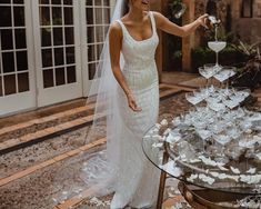 a woman standing in front of a table filled with wine glasses and champagne flutes on it