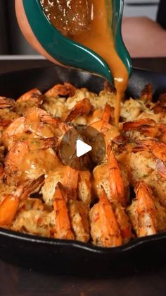 someone is pouring sauce on some food in a skillet with shrimp and other foods