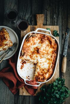 a casserole dish on a cutting board with a fork and knife next to it