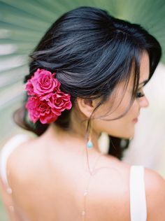 a woman holding an umbrella with flowers in her hair and wearing a white tank top