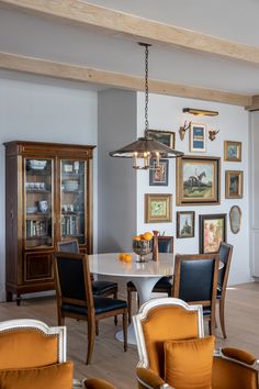 a dining room table with chairs and pictures on the wall above it, along with other furniture