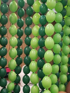 there are many green balloons hanging from the ceiling