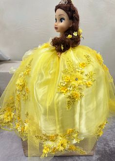 the doll is wearing a yellow dress with flowers on it