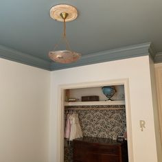 a room with a bed, dresser and light fixture hanging from it's ceiling