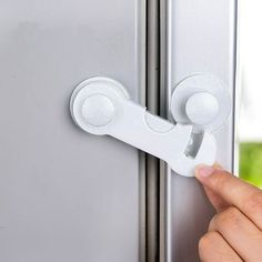 a person is holding the handle on a refrigerator door with it's left hand