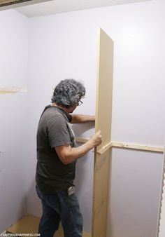 a man standing in front of a wall with a piece of wood on top of it