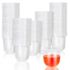 a bunch of cups that are sitting next to each other on a white surface with red liquid in the middle