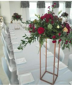 there is a vase with flowers in it on top of a long dining room table