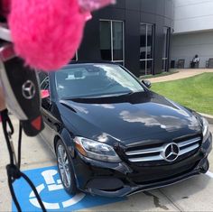 a black car parked in front of a building with a pink flower on the ground