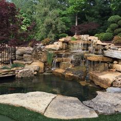 a small pond surrounded by rocks and water features a waterfall that flows into the pool