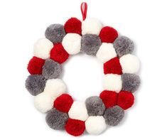 a red, white and grey wreath hanging from a string on a white wall ornament