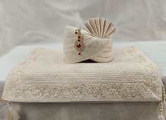 a white blanket and pillow on top of a bed with beaded trimmings