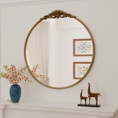 a mirror sitting on top of a mantle next to a vase with flowers