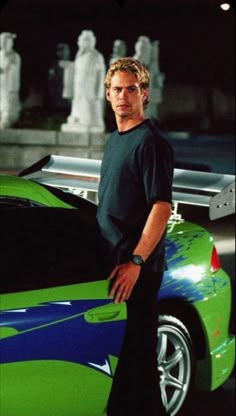 a man standing next to a green sports car