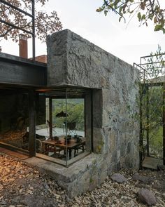 an outdoor dining area in front of a stone building with glass walls and doors on the outside