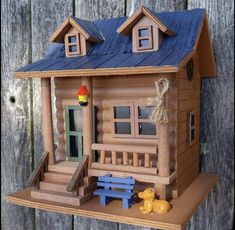 a small wooden house with a blue roof and two yellow ducks sitting in front of it