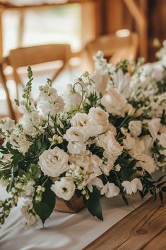 white flowers are sitting on a table with chairs in the background