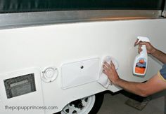 a man is cleaning the side of a white truck with a spray bottle and rag