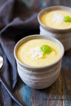 two bowls filled with soup and garnished with green leafy leaves on top