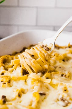 a spoon full of macaroni and cheese in a white casserole dish