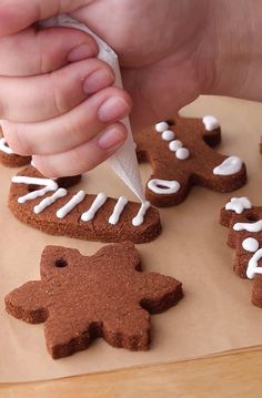 someone is decorating gingerbreads with icing on a sheet of brown paper