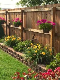 a wooden fence with flower pots on the top and flowers in the bottom, along side it