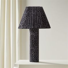 a black lamp sitting on top of a white shelf next to a curtained window