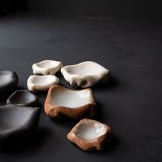 some white and brown rocks on a black surface with one rock in the middle, and two smaller ones sitting next to each other