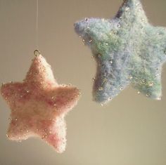 two small stars hanging from strings in the shape of felt or wools, one pink and one blue