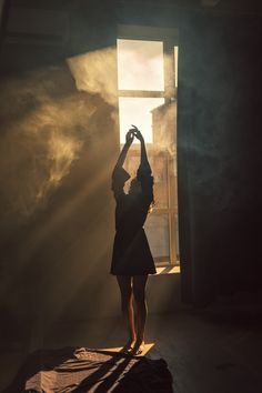 a woman standing in front of a window with the sun shining down on her head