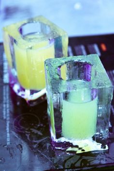 two glasses filled with yellow liquid sitting on top of a table next to each other