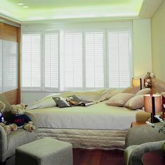 a bed room with a neatly made bed and two teddy bears sitting on the pillows