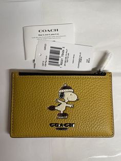 a yellow coach wallet with a cartoon character on the front, and an id card holder attached to it