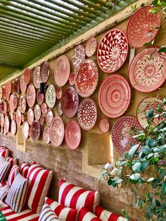 red and white plates are hanging on the wall next to couches with striped pillows