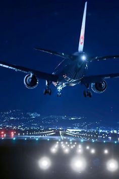 an airplane is taking off from the runway at night with city lights in the background