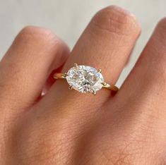 a woman's hand with a diamond ring on top of her finger, showing the center stone